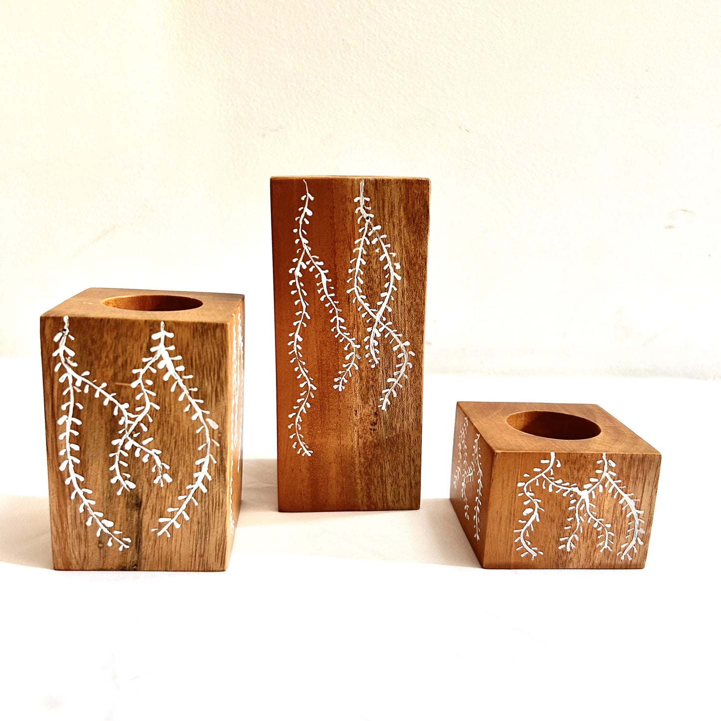 Handcrafted set of 3 candle holders made of Natural solid mahogany wood is a perfect way to make your rooms cozy and beautiful. Hand-drawn with beautiful motifs when placed on a coffee/dining/corner table, accents the beauty,  brightens the space making the room welcoming, calm and peaceful. These candle holders of different heights could be arranged in any way as per the space it is kept.  Rustic decor accessories, gifting for birthday, wedding anniversary, housewarming. 